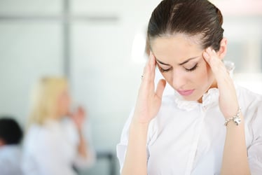 women with her hands at her temples and eyes closed stressed and overwhelmed