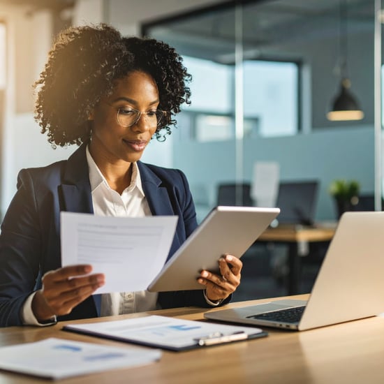 woman sits at desk look at files and papers. she is very organized and pulled together.