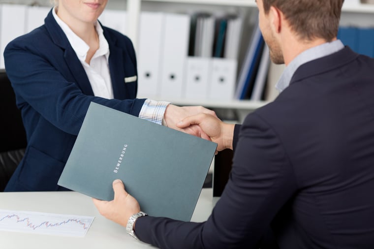 business woman shaking hands with a business man at her desk