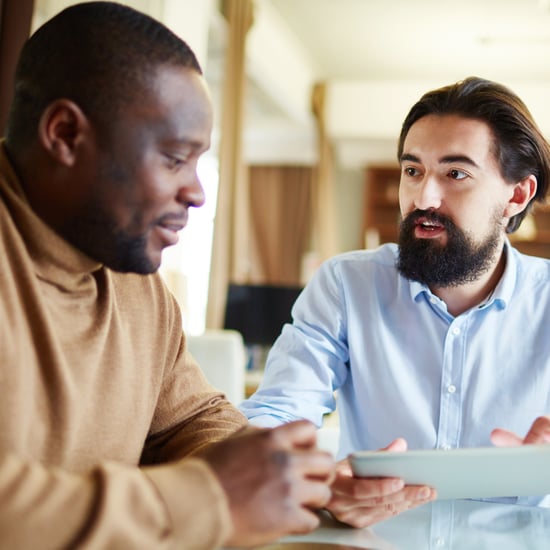 Two men dressed in business casual clothing have a discussion about employee engagement programs.