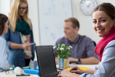 coworkers collaborating around a table while a women is working on her laptop