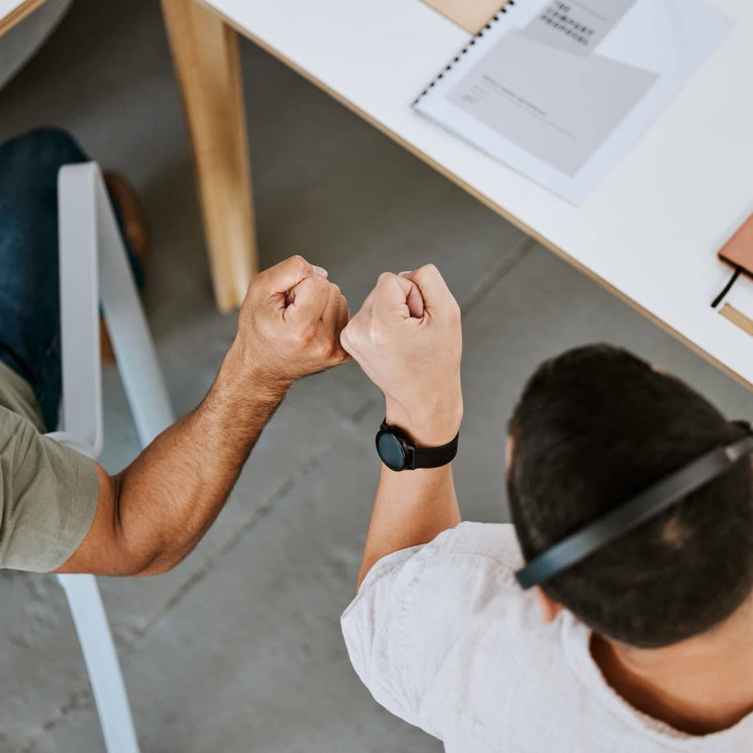 Two men bumping fists at work. 