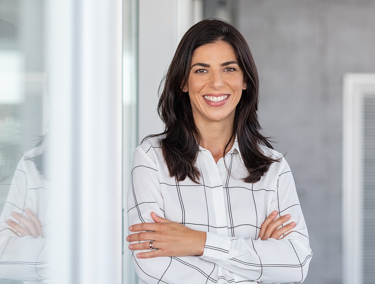 Woman smiling while leaning against glass wall. 