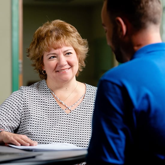 Woman helping man with paperwork. 