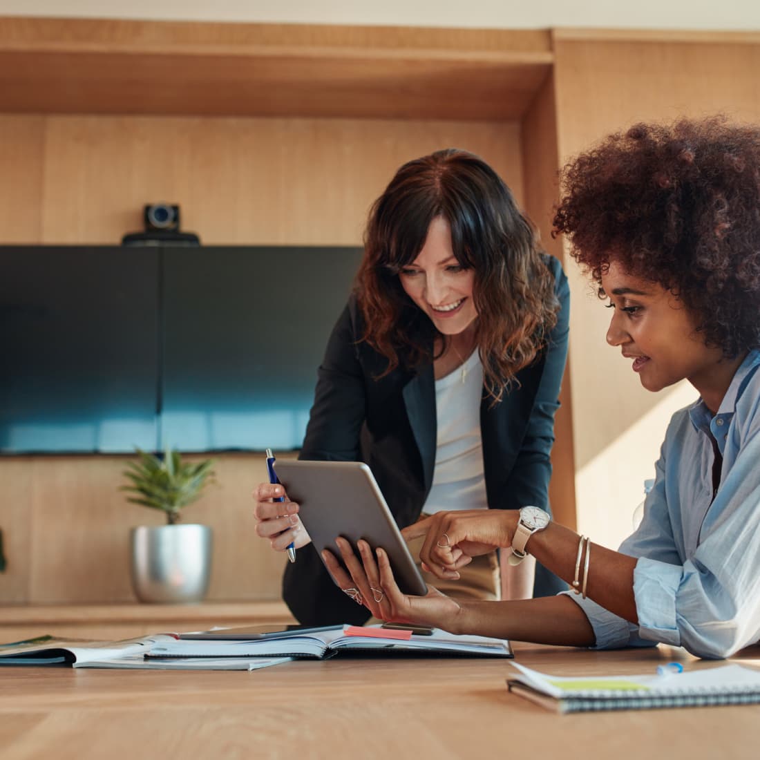 Two women helping one another out on tablet. 