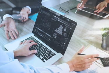 business documents on office table with smart phone and laptop computer and graph financial with social network diagram and three colleagues discussing data in the background